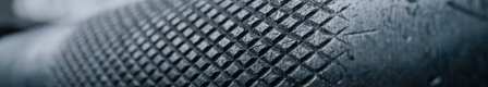Extreme macro photograph of worn barbell knurling, cold window light in the background.